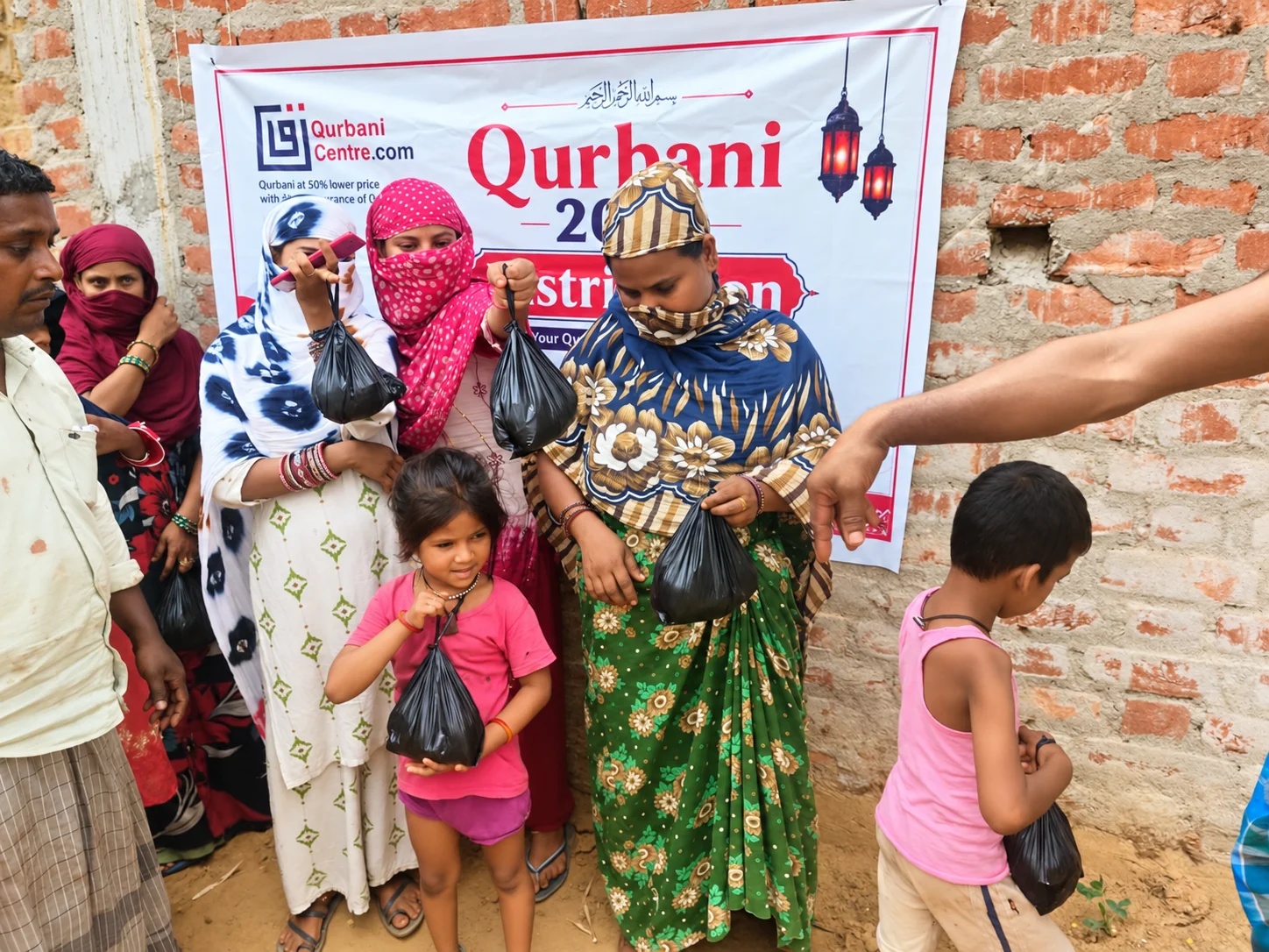 Women and children holding small packets in front of a Qurbani Centre distribution banner